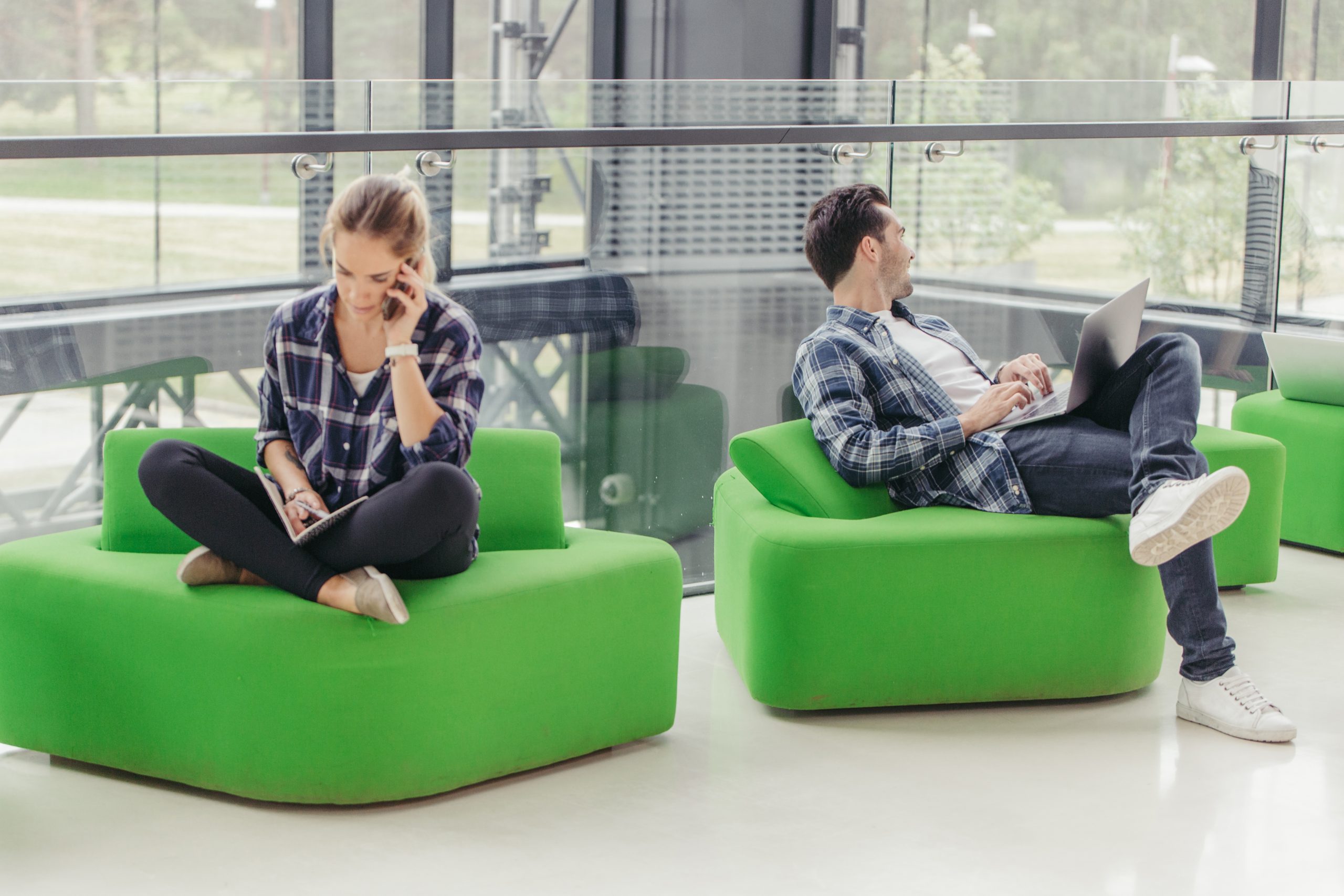 Two employees sat on comfortable seating in office space