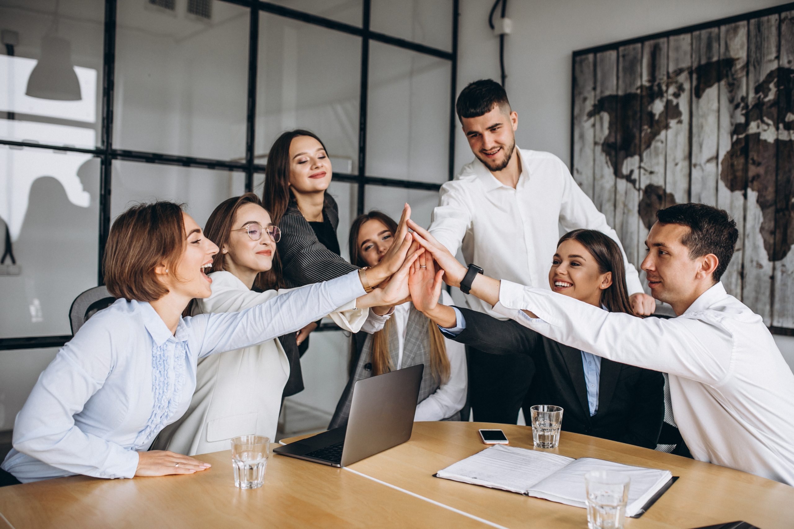 Team of employees high fiving each other in office