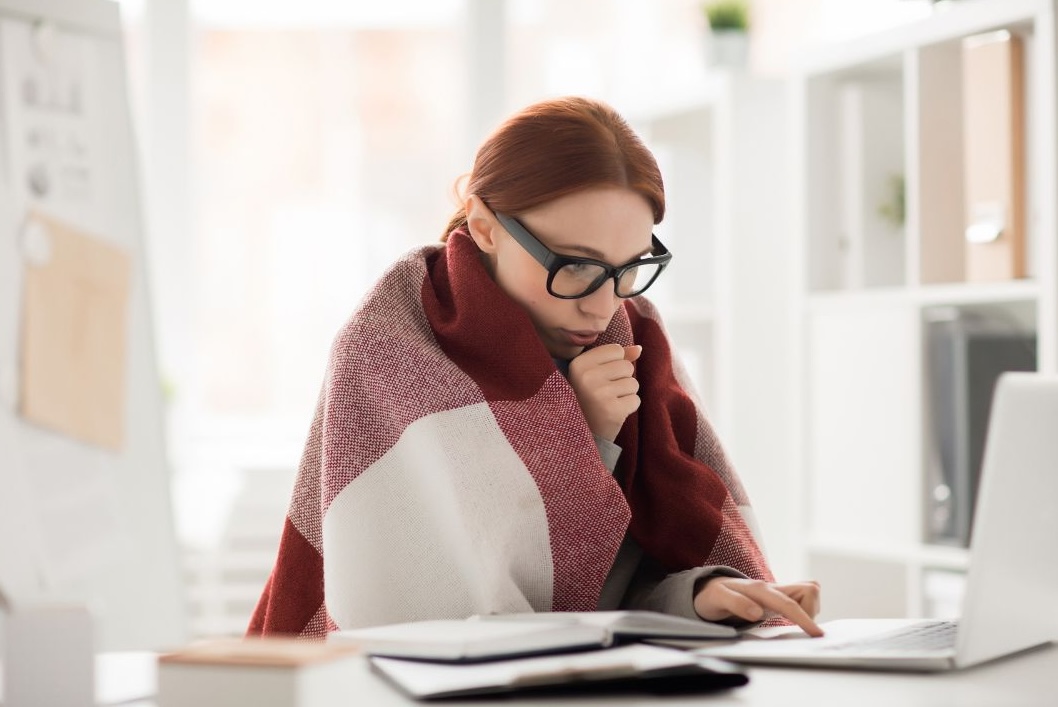 woman sitting in blanket in cold office